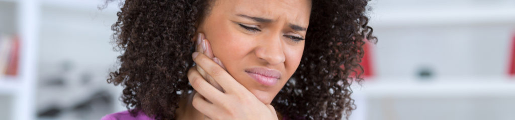 woman touching her jaw because of TMD pain