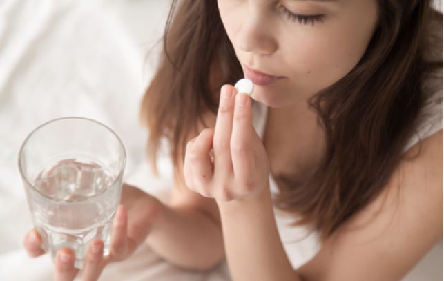 Young women taking pill with water through oral sedation before her dental surgery
